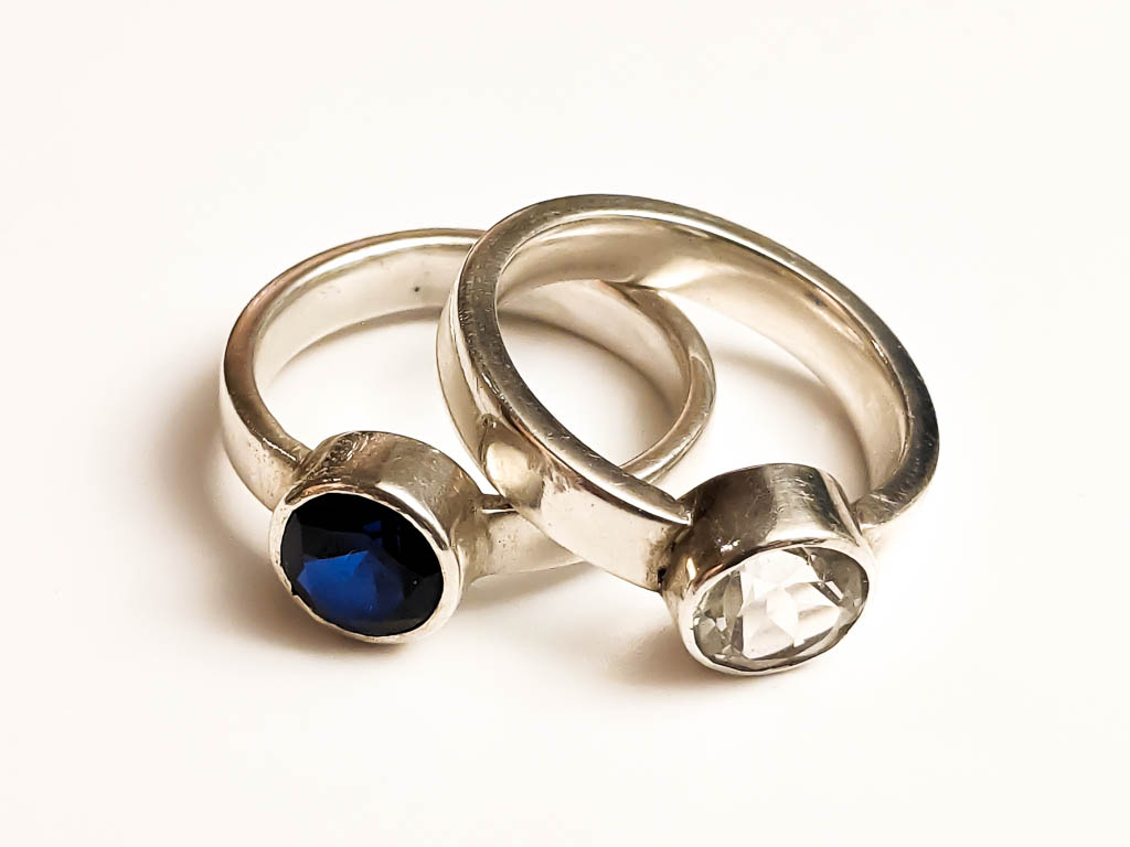 Sterling silver rings, one with a lab-created blue sapphire and one with a white topaz