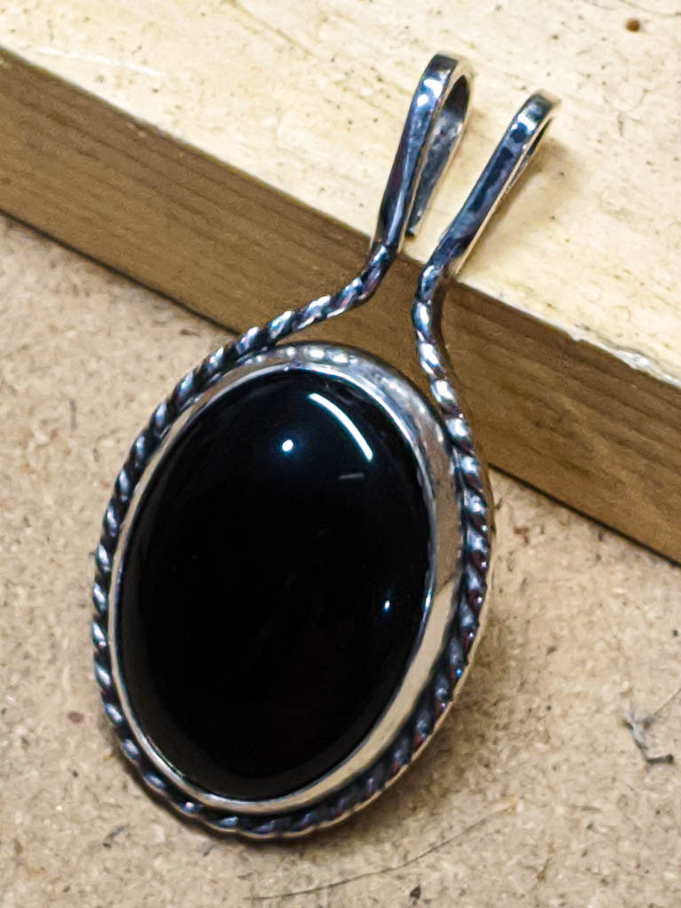 Black onyx oval cabochon pendant on the workbench, before adding a chain