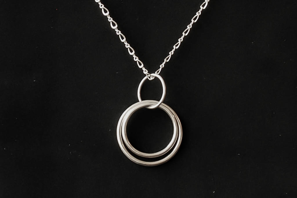 Sterling silver concentric hoops, hanging from a smaller hoop on a sterling silver figure eight chain